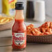 A bottle of Frank's RedHot Original Cayenne Pepper Sauce next to a plate of chicken wings.