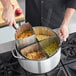 A chef uses a Choice stainless steel strainer basket to drain pasta.