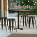 A Lancaster Table & Seating rectangular counter height table with a brown textured top and cross base plates on a patio.