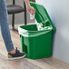 A person putting a white tissue in a Lavex green rectangular step-on trash can.