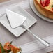 An Acopa Edgeworth stainless steel cake server serving a slice of cake on a plate.