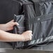 A person holding a Vesture heavy-duty black thermal food pan carrier bag.