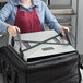 A person in a red apron using a Vesture aluminum shelf to carry a large box with a strap around it.
