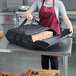 A woman holding a Vesture NextPhase insulated pizza delivery bag with pizza boxes inside.