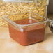 A Carlisle amber plastic food pan with pasta and red sauce on a hotel buffet counter.