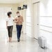 A man and woman walking down a hospital hallway with an AeraMax air purifier.