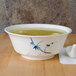 A Blue Bamboo melamine bowl filled with soup on a counter with a spoon.