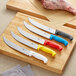 A group of Choice cimeter knives with yellow handles on a cutting board.