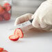 A person in gloves uses a Choice paring knife to cut a strawberry.