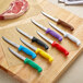 A group of Choice utility knives with colorful handles on a cutting board.