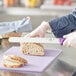 A person cutting bread with a Choice serrated bread knife.