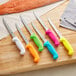 A group of Choice fillet knives with colorful handles on a cutting board.