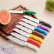 A group of Choice Santoku knives with different colored handles on a cutting board next to a watermelon.