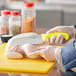 A person using a Choice Santoku knife with a neon yellow handle to cut chicken.