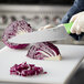 A person using a Choice chef knife to cut cabbage.