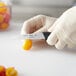 A person in gloves uses a Choice serrated paring knife to cut a tomato.
