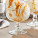 A Pasabahce stemmed dessert glass filled with ice cream and caramel sauce.