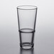 A close up of a Pasabahce clear beverage glass with a half full beverage.