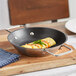 A Vigor SS1 Series stainless steel non-stick fry pan with omelette in it on a wood surface.