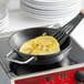A Vigor SS1 Series stainless steel non-stick fry pan with food cooking on a stove.