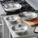 A Vigor stainless steel fry pan with dual handles on a counter in a professional kitchen.