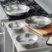 A Vigor stainless steel fry pan with aluminum-clad bottom and dual handles on a professional kitchen counter.