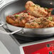 A Vigor stainless steel non-stick fry pan with chicken and vegetables cooking in it.