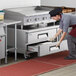 A chef using the refrigerated drawers on a Cooking Performance Group countertop griddle and chef base.
