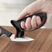 A hand holding a black Choice handheld knife sharpener sharpening a knife.