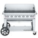 A Crown Verity stainless steel mobile grill with a windguard and wheels.