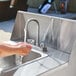 A person washing their hands in a Crown Verity portable sink.