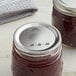 Two jars of jam with Kerr Regular Mouth canning jar lids on a table.