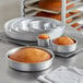A round metal cake pan with several round cakes in them.