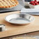 A Baker's Mark aluminum pie pan with a pie on a cutting board.
