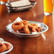 A plate of fried onion rings on a Baker's Mark pie pan on a table.