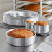 A group of Choice round aluminum cake pans with food in them.