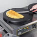 A person cutting a crepe on a Carnival King dual non-stick crepe maker.