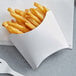 A close-up of french fries in a white paper tray.