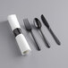 A white napkin and black plastic cutlery set with fork and spoon.