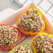 A white dish of stuffed peppers with Furmano's tri-color quinoa and peas.
