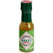 A close up of a small TABASCO® Green Hot Sauce bottle.