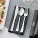 A black and white striped napkin roll with silverware inside, including a metallic silver fork and knife.