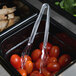 A pair of Cambro plastic tongs in a bowl of cherry tomatoes.