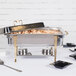 A Vollrath Classic Brass Chafing Dish on a table with food in it.