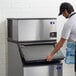 A man in a white shirt opening the door to a Manitowoc Indigo NXT air cooled ice machine.
