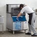 A man installing a Manitowoc Indigo NXT air cooled ice machine on a counter.