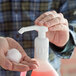 A person using a Noble Chemical plastic foaming soap pump to dispense white soap.