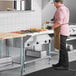 A man in a brown apron using a ServIt natural gas steam table in a professional kitchen.