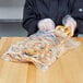 A person in a black coat holding a pretzel in a 13" x 15" resealable plastic bag.
