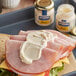 A sandwich with ham and cheese on a plate with a jar of Hellmann's Real Mayonnaise.